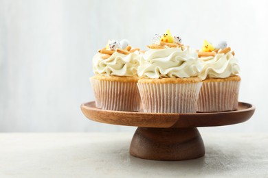 Photo of Tasty Easter cupcakes with vanilla cream on gray table, space for text