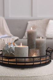 Tray with burning candles on ottoman indoors