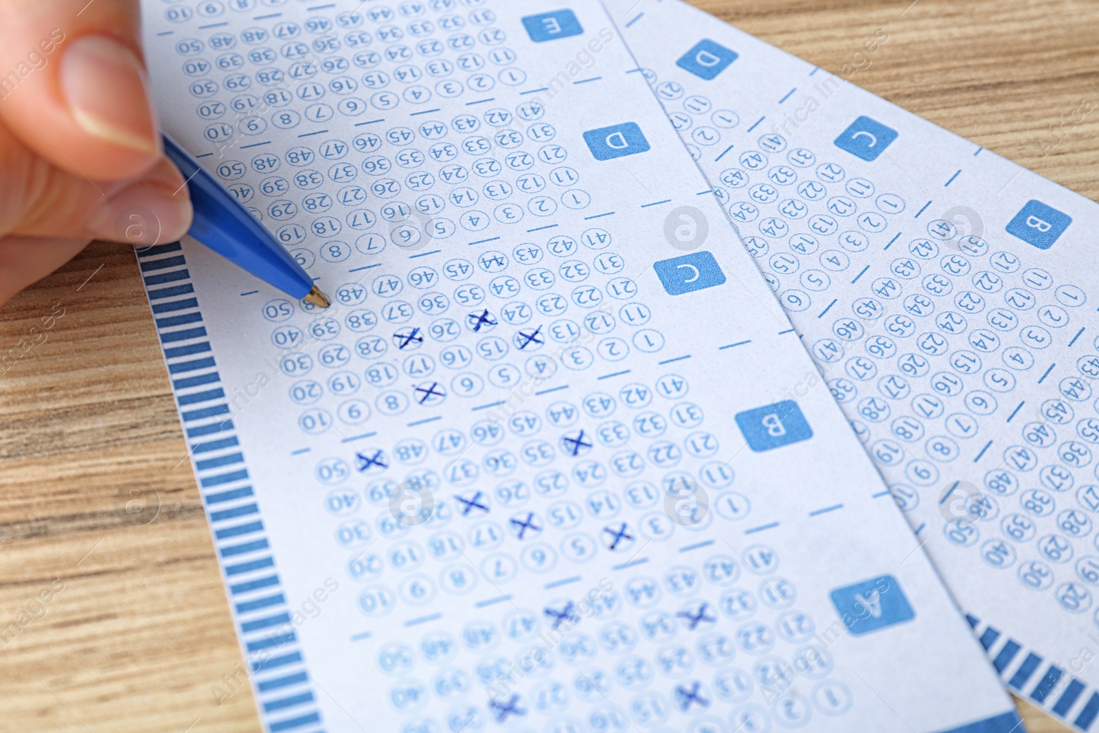 Photo of Woman filling out lottery tickets with pen on wooden table, closeup. Space for text