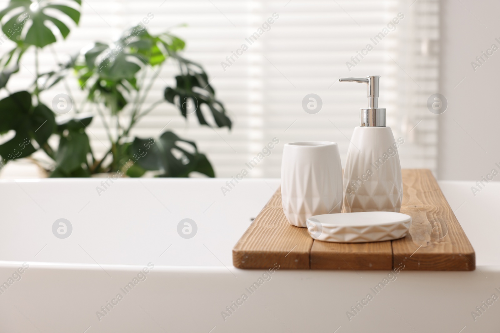 Photo of Set of different bath accessories on tub in bathroom, space for text