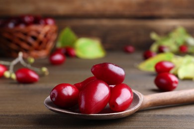 Fresh ripe dogwood berries with spoon on wooden table, closeup