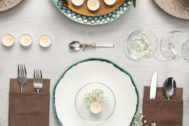 Elegant table setting with green plants on white wooden background, flat lay