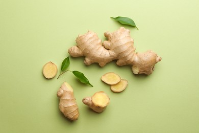 Photo of Fresh ginger with leaves on light pale green background, flat lay