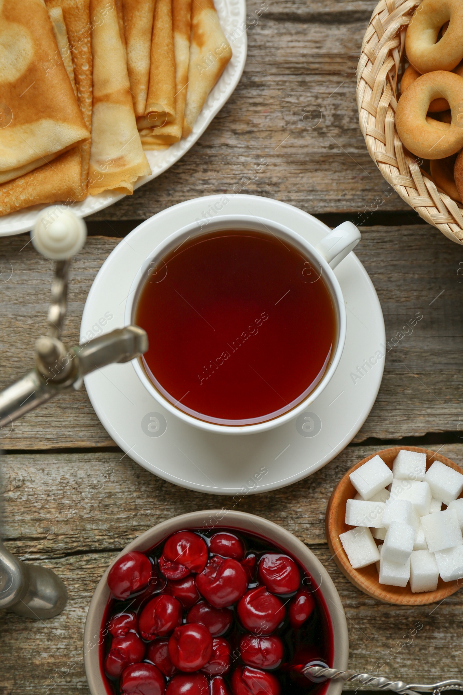 Photo of Metal samovar with cup of tea and treats on wooden table, flat lay