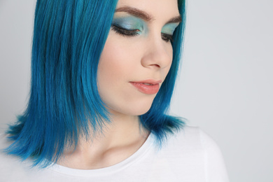 Photo of Young woman with bright dyed hair on light grey background, closeup