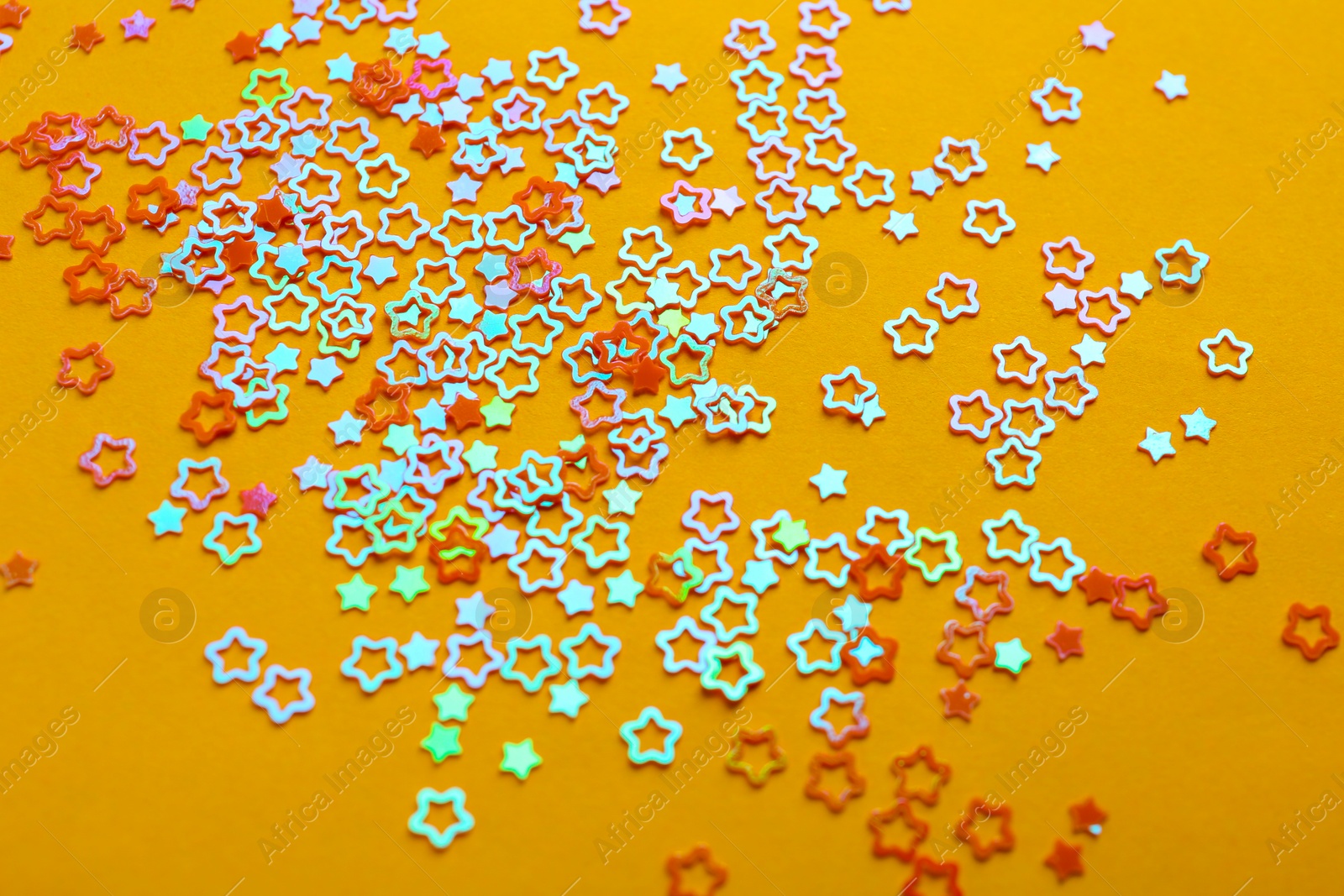 Photo of Shiny bright star shaped glitter on pale orange background