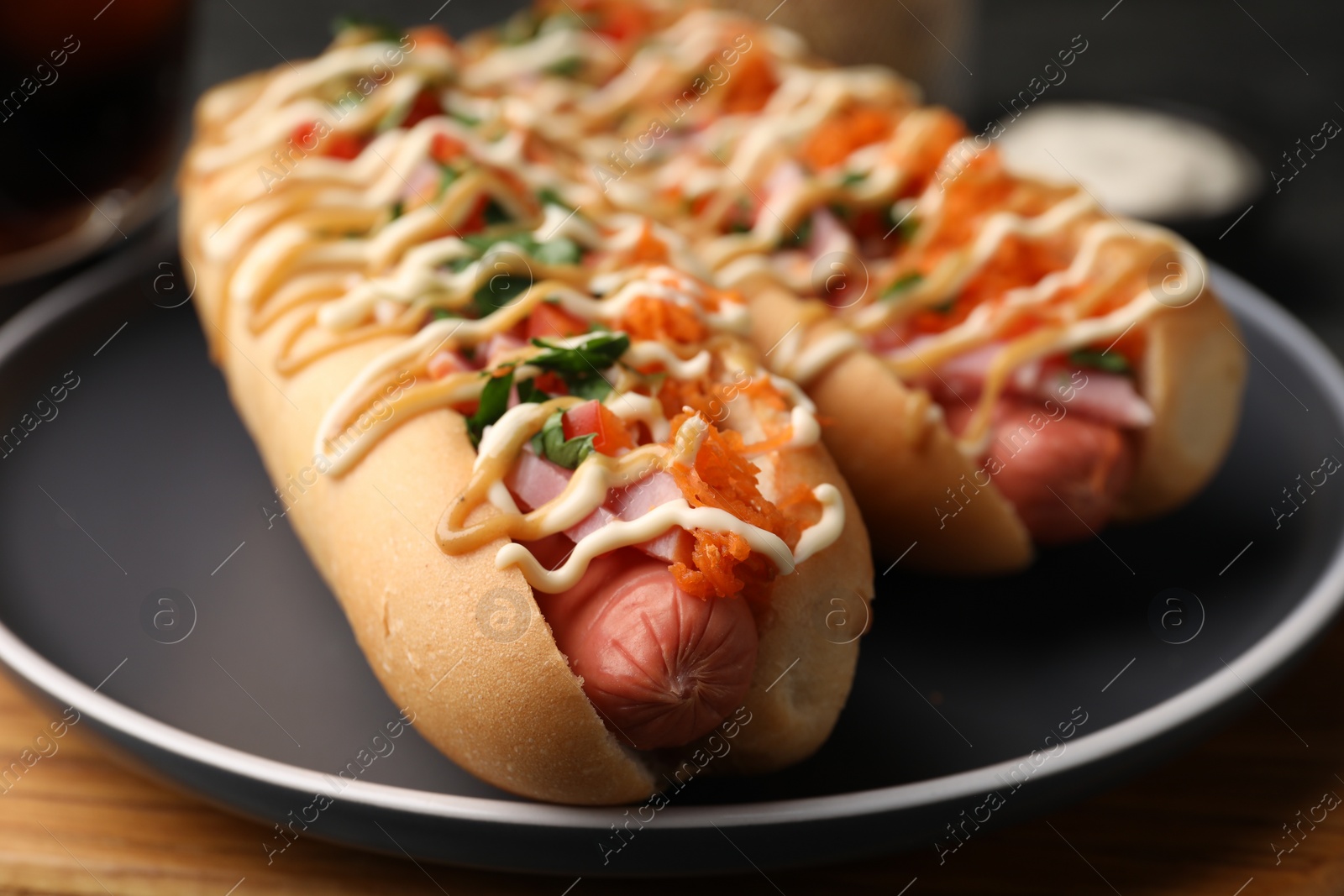 Photo of Delicious hot dogs with bacon, carrot and parsley on table, closeup