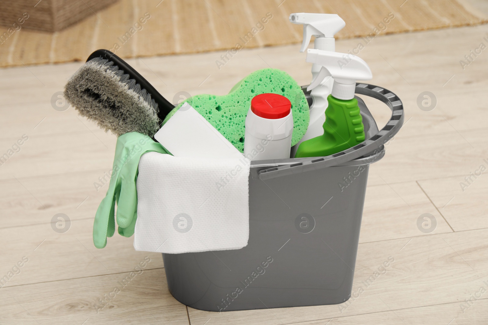 Photo of Different cleaning products in bucket on floor indoors
