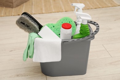 Different cleaning products in bucket on floor indoors