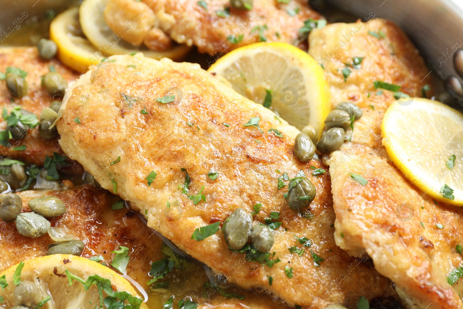 Photo of Delicious chicken piccata with herbs and lemons as background, closeup