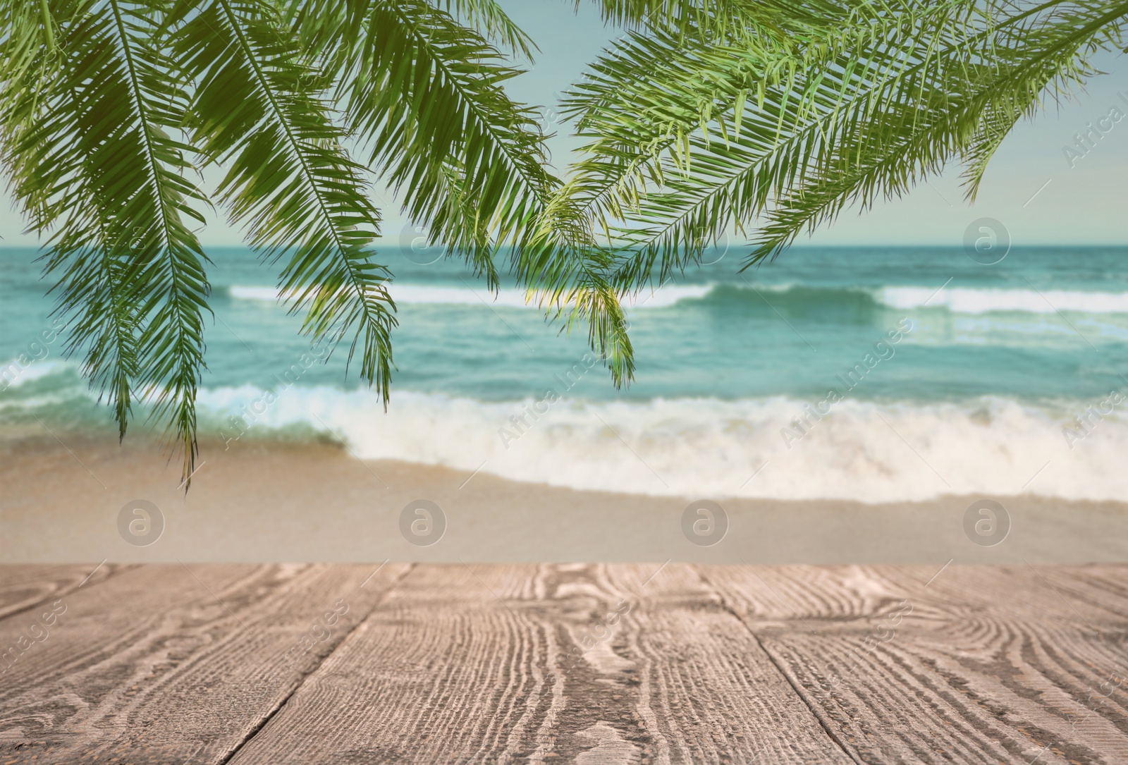 Image of Wooden table under green palm leaves on beach