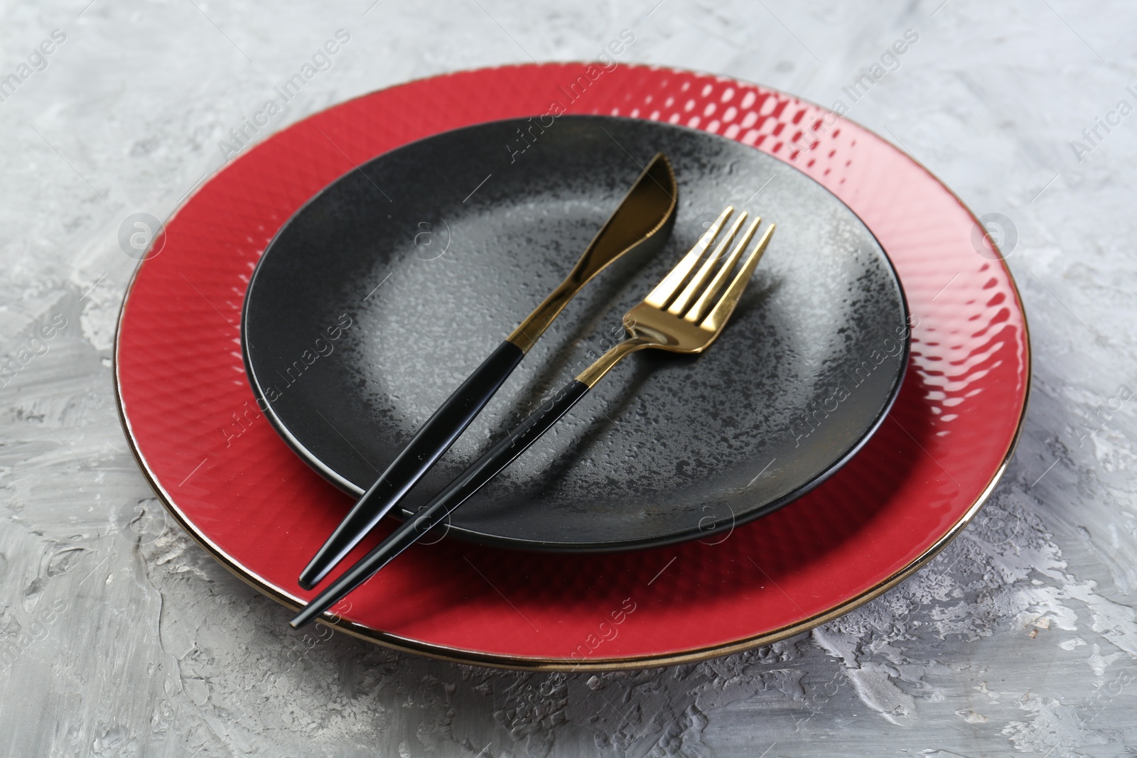 Photo of Clean plates and cutlery on gray table, closeup