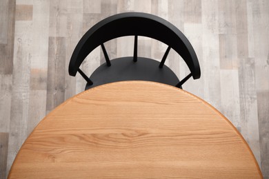 Photo of Round wooden table and black chair indoors, top view