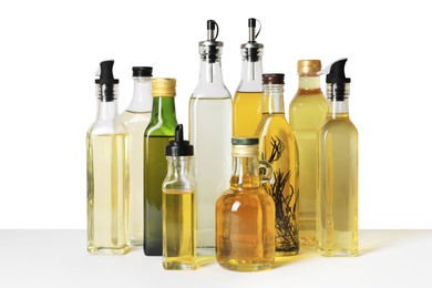 Bottles of different cooking oils on white background