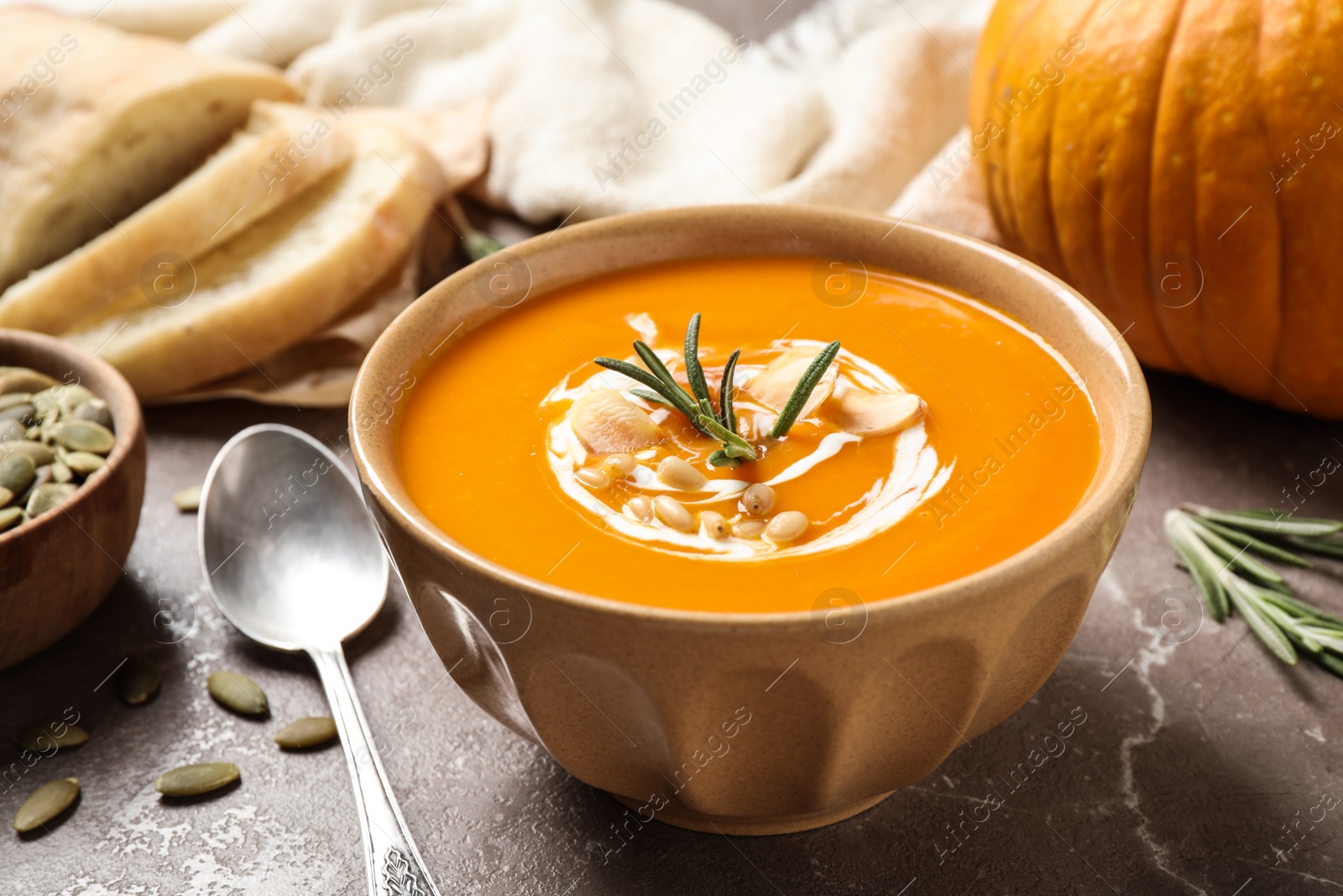 Photo of Delicious pumpkin soup in bowl on marble table