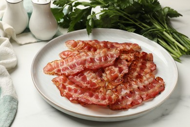 Plate with fried bacon slices and parsley on white table, closeup