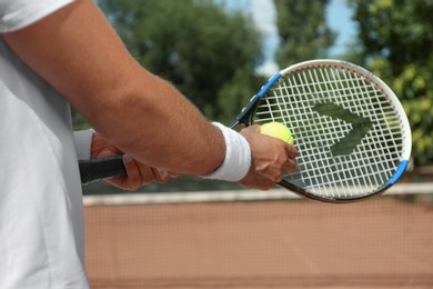 Sportsman preparing to serve tennis ball at court, closeup