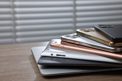 Photo of Many different modern gadgets on wooden table indoors. Space for text