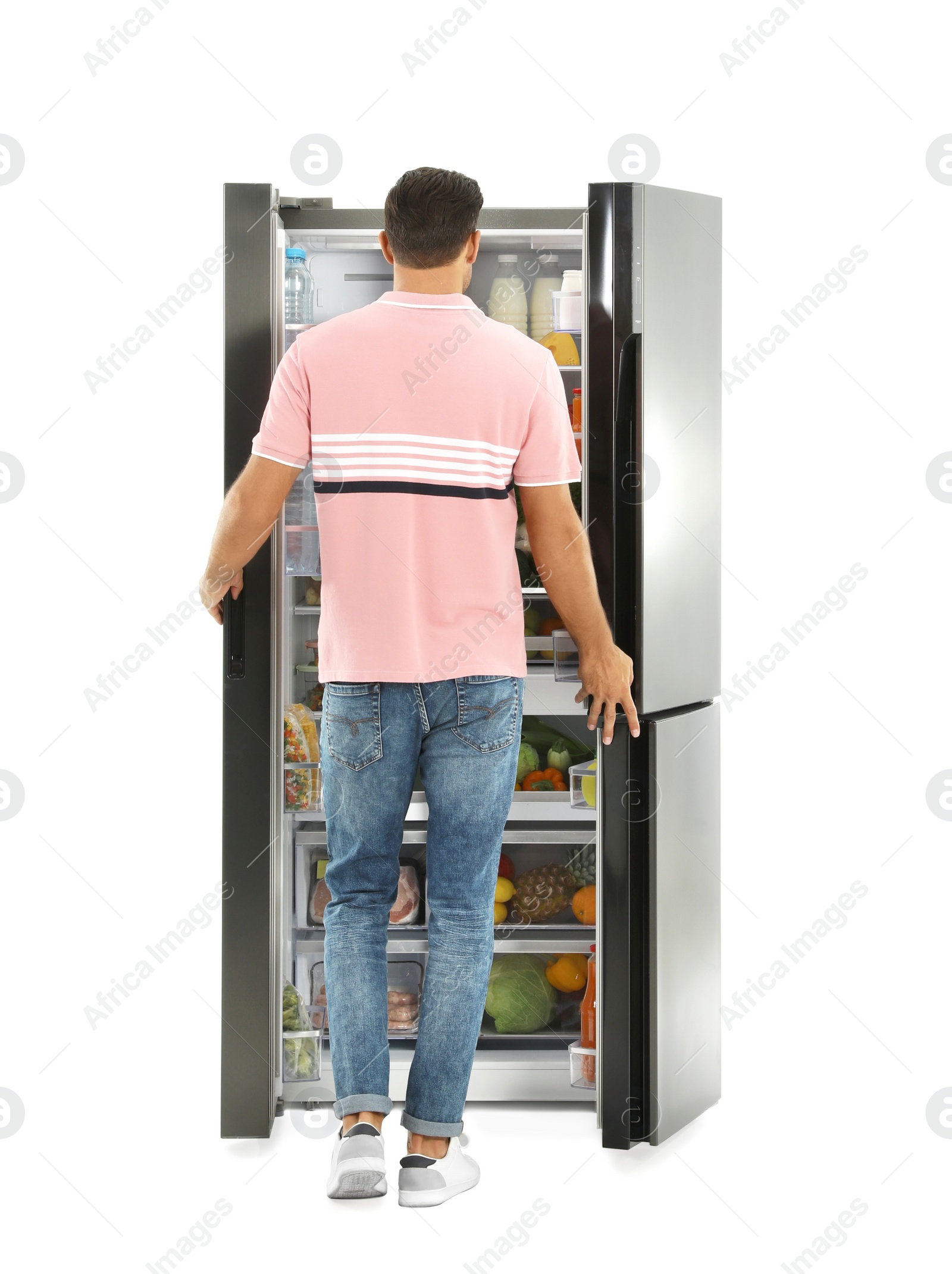 Photo of Man near open refrigerator on white background, back view