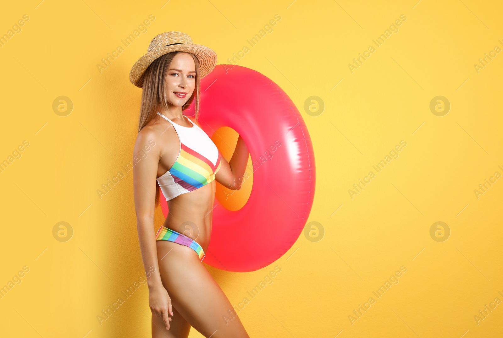 Photo of Sexy young woman in bikini with inflatable ring on color background