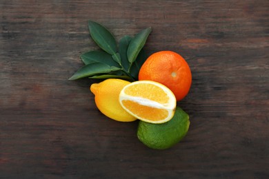 Photo of Different citrus fruits and leaves on wooden table, flat lay
