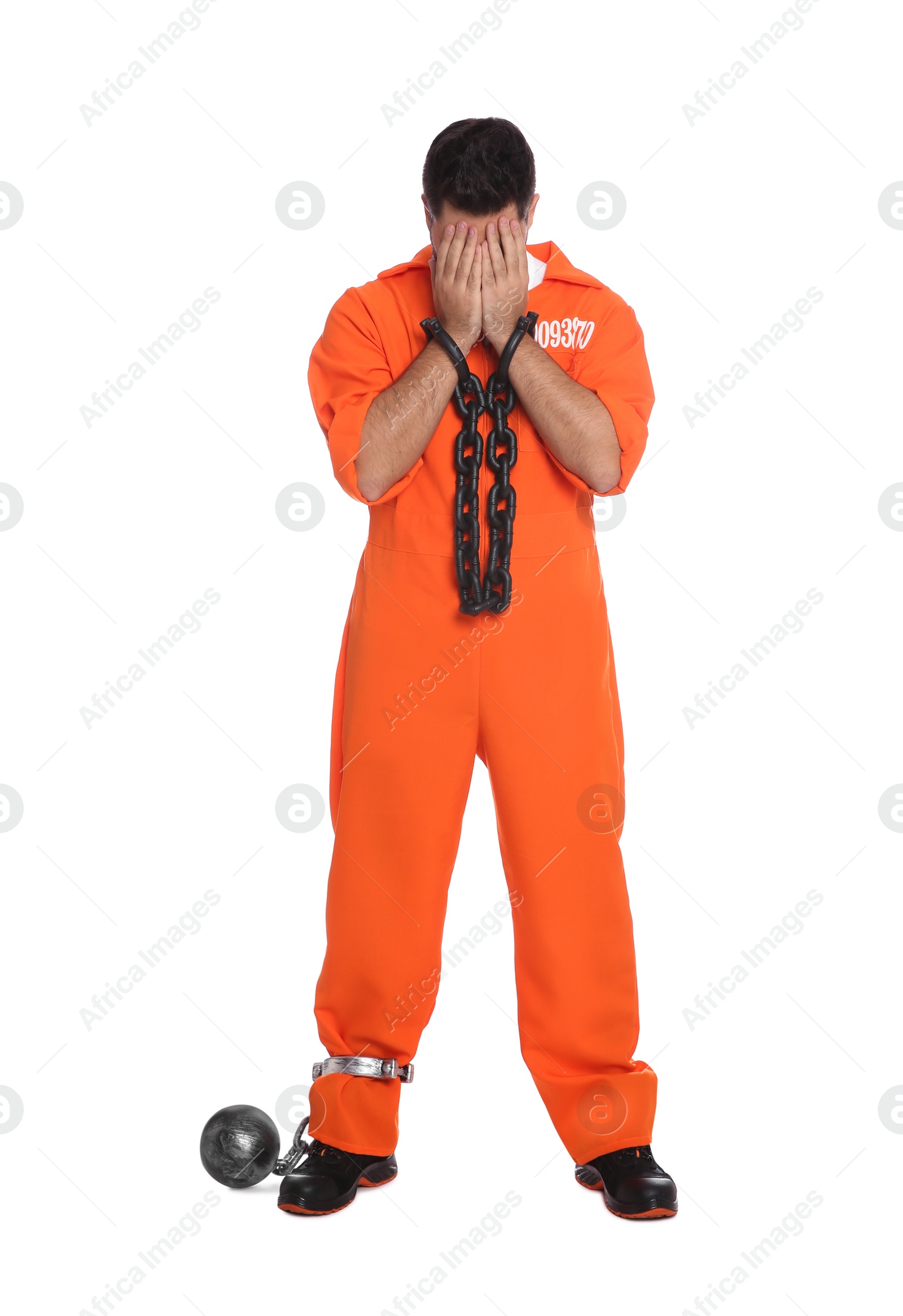 Photo of Prisoner in jumpsuit with chained hands and metal ball on white background