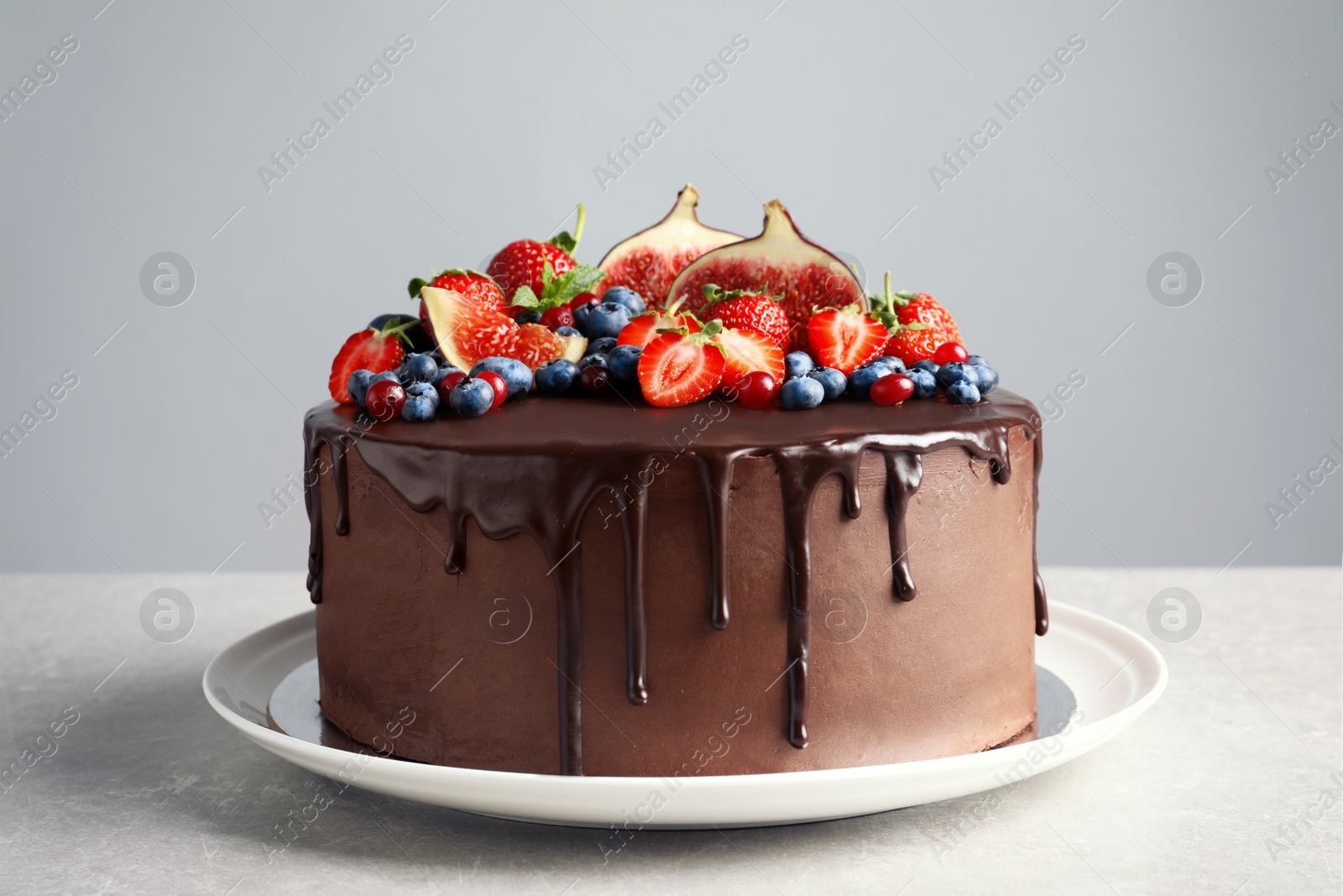 Photo of Fresh delicious homemade chocolate cake with berries on table against gray background