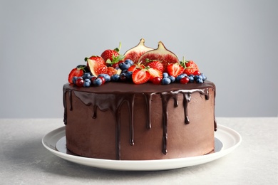 Photo of Fresh delicious homemade chocolate cake with berries on table against gray background