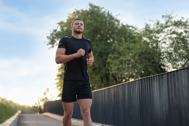 Attractive sporty man in fitness clothes jogging outdoors