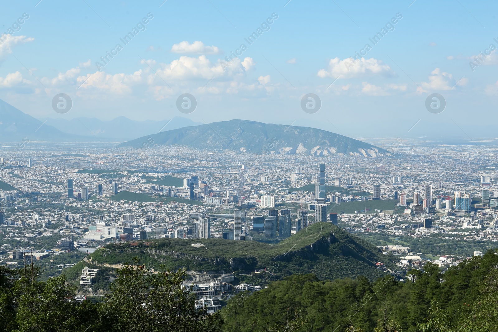 Photo of Picturesque view of city with trees, mountains and buildings under beautiful sky