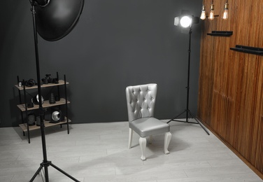 Photo of Stylish silver chair and professional equipment in photographer's studio