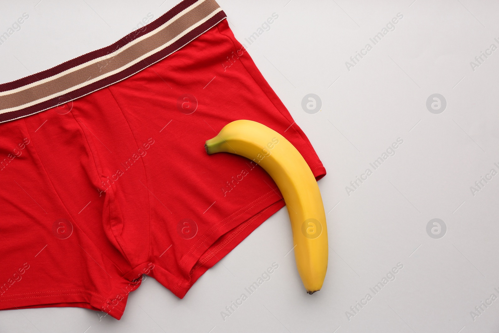 Photo of Men's underwear and banana on light background, flat lay. Potency problem concept