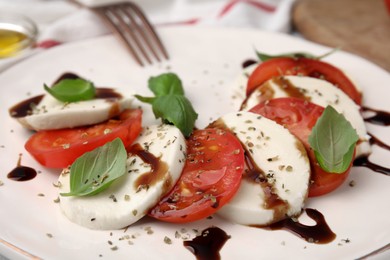 Photo of Delicious Caprese salad dressing with balsamic vinegar on plate, closeup