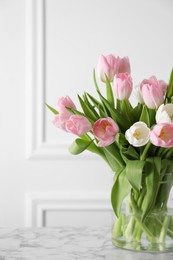 Photo of Beautiful bouquet of tulips in glass vase on white marble table