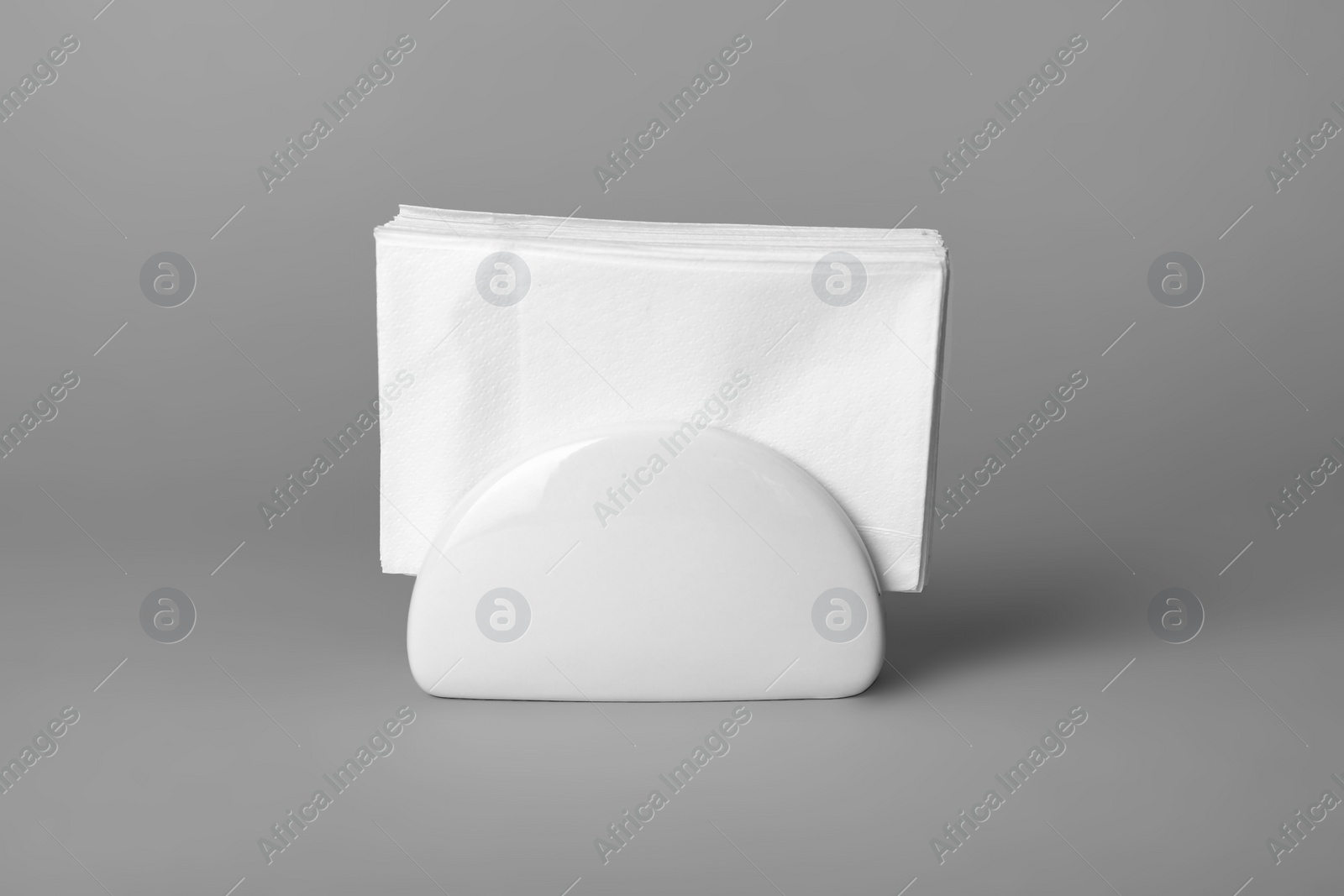 Photo of Ceramic napkin holder with paper serviettes on gray background