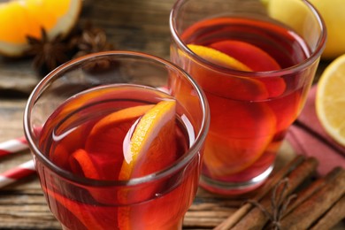 Photo of Aromatic punch drink and ingredients on wooden table, closeup