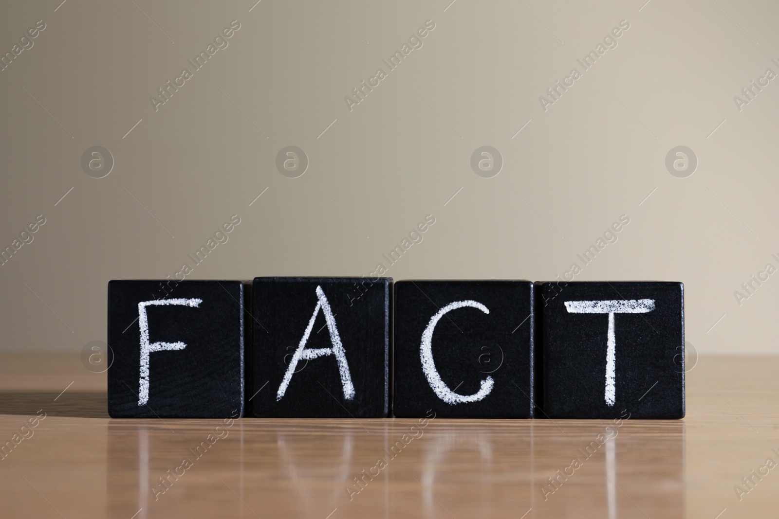Photo of Word FACT made with black cubes on wooden table
