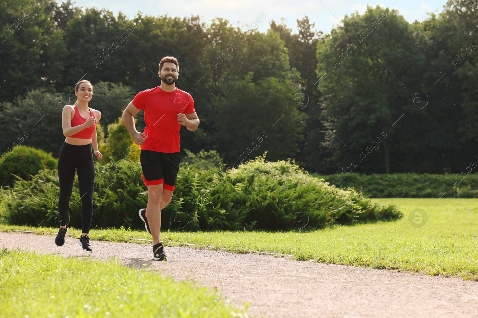 Photo of Healthy lifestyle. Happy couple running outdoors on sunny day, space for text