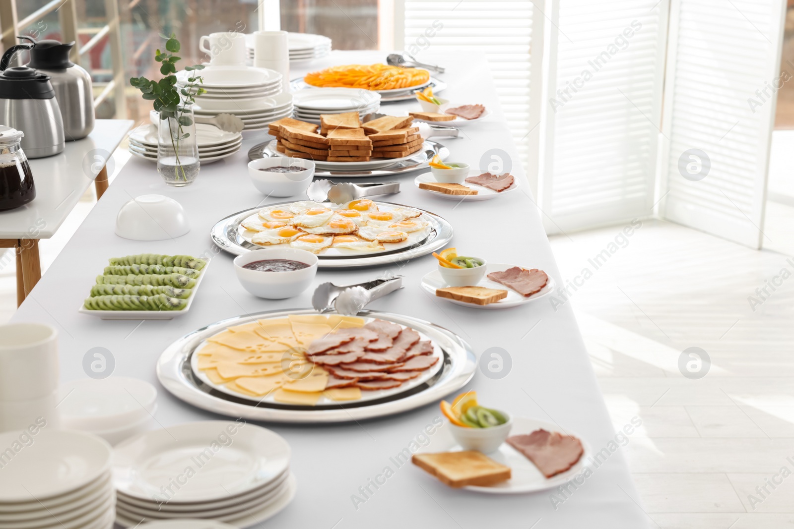 Photo of Clean dishware and different meals for breakfast on white table indoors. Buffet service