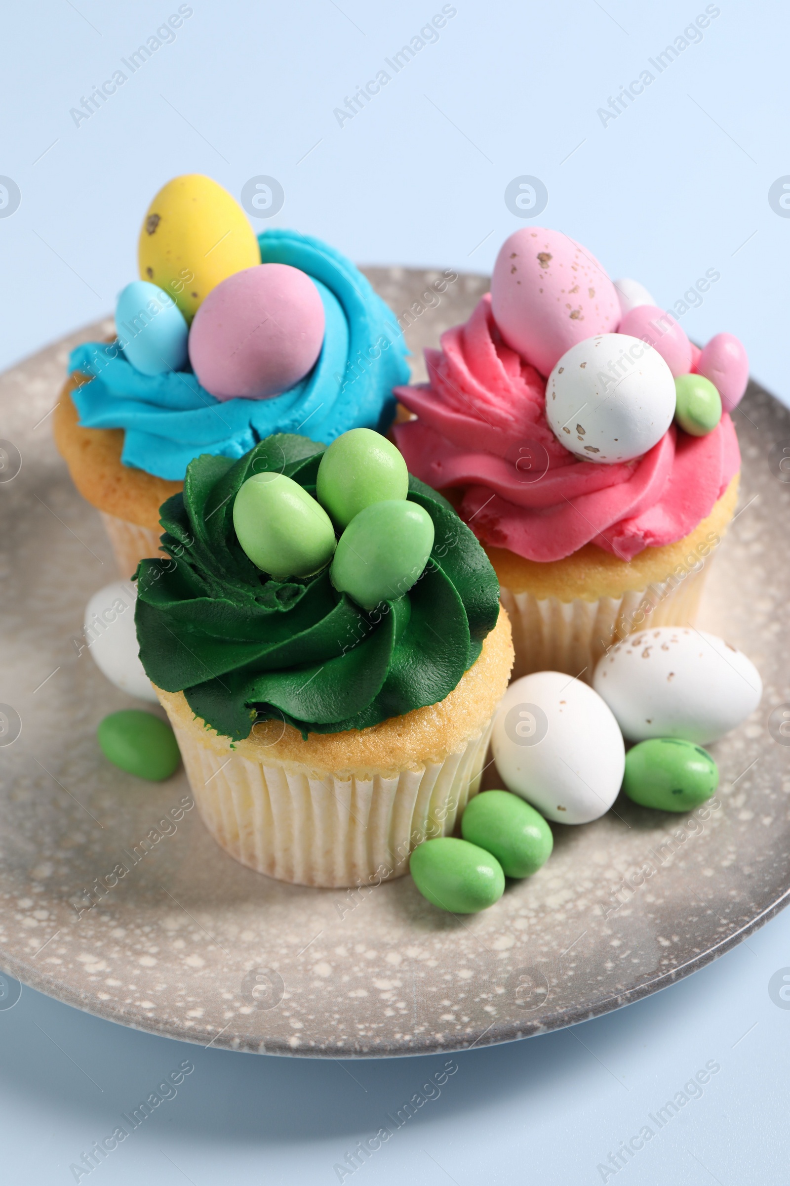 Photo of Tasty cupcakes with Easter decor on light blue background