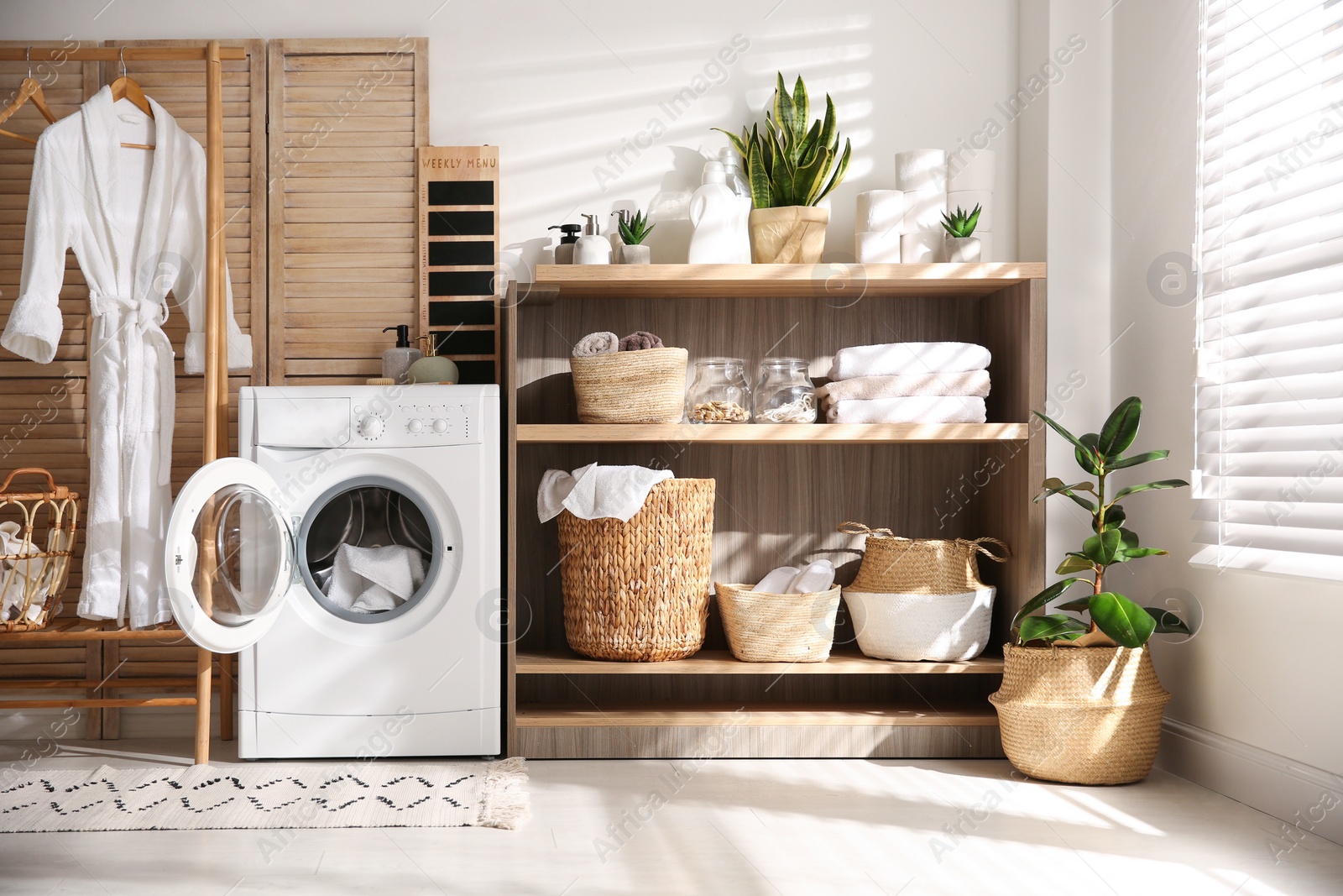 Photo of Modern washing machine and shelving unit in laundry room interior