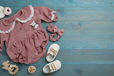 Photo of Flat lay composition with baby clothes and accessories on light blue wooden table. Space for text