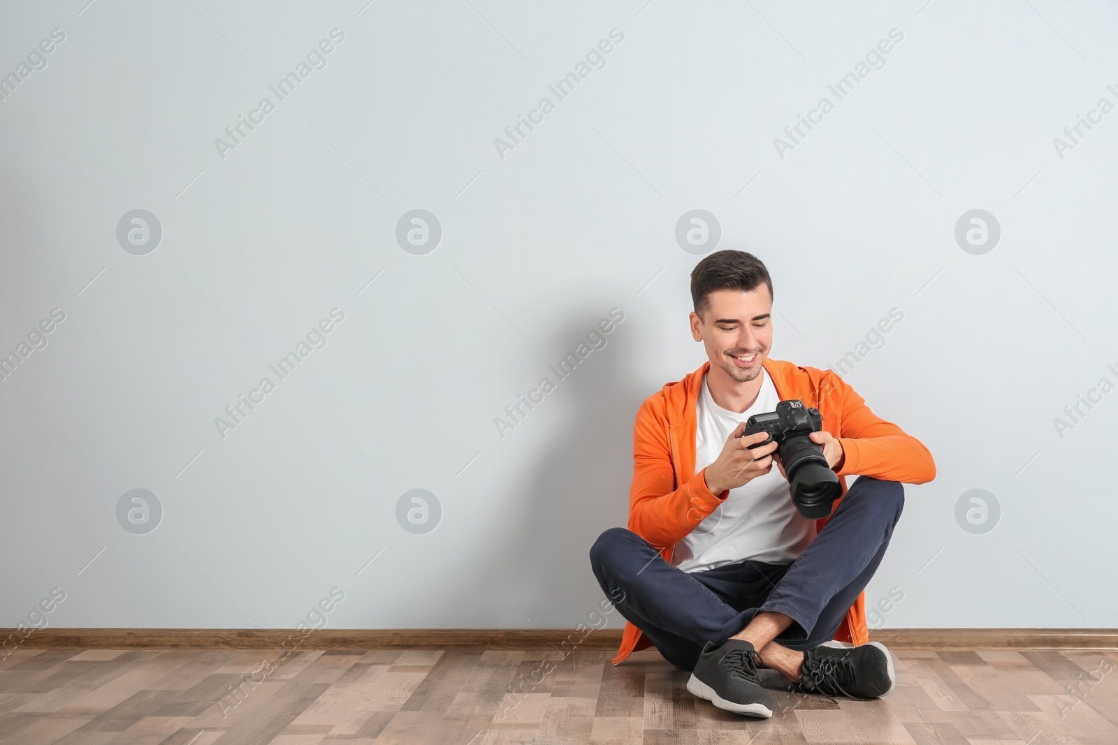 Photo of Male photographer with camera near light wall