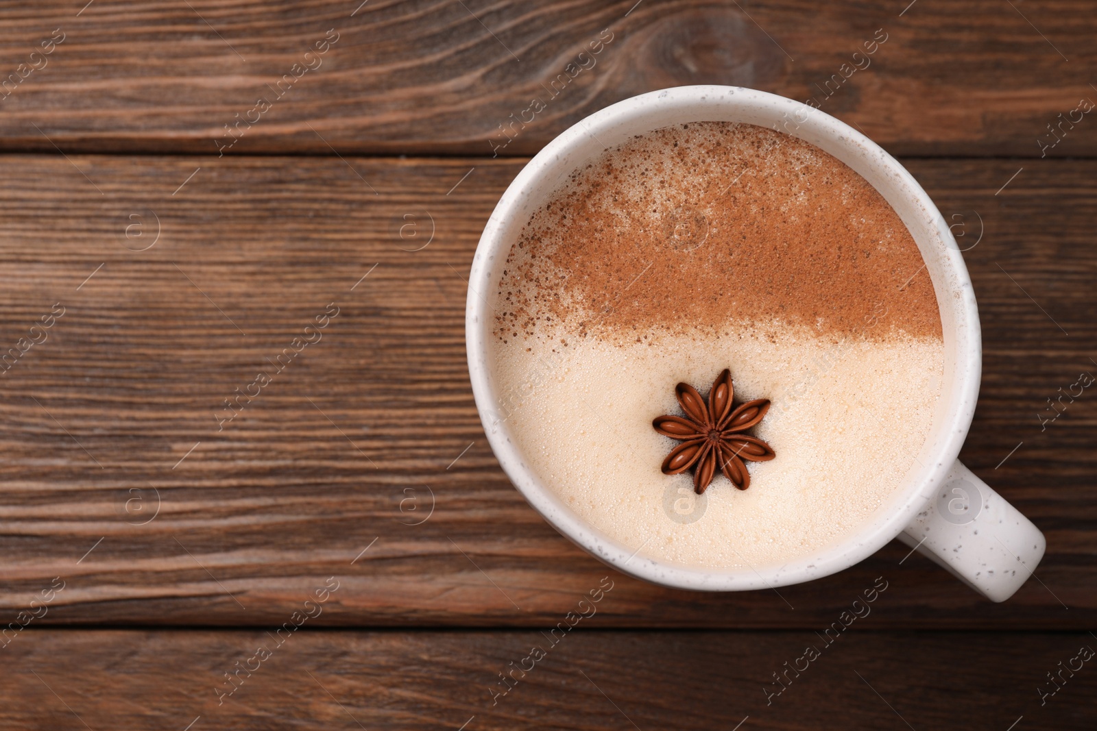 Photo of Delicious eggnog with anise on wooden table, top view. Space for tex