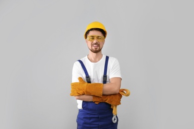 Photo of Male industrial worker in uniform on light background. Safety equipment