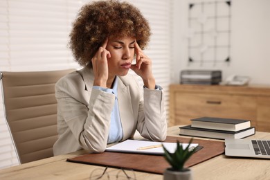 Woman suffering from headache at workplace in office