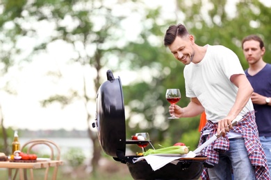 Young people having barbecue with modern grill outdoors