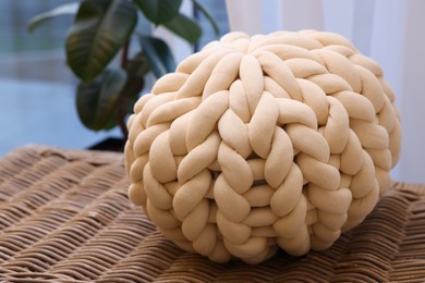 Photo of Beautiful knitted pillow near window in room