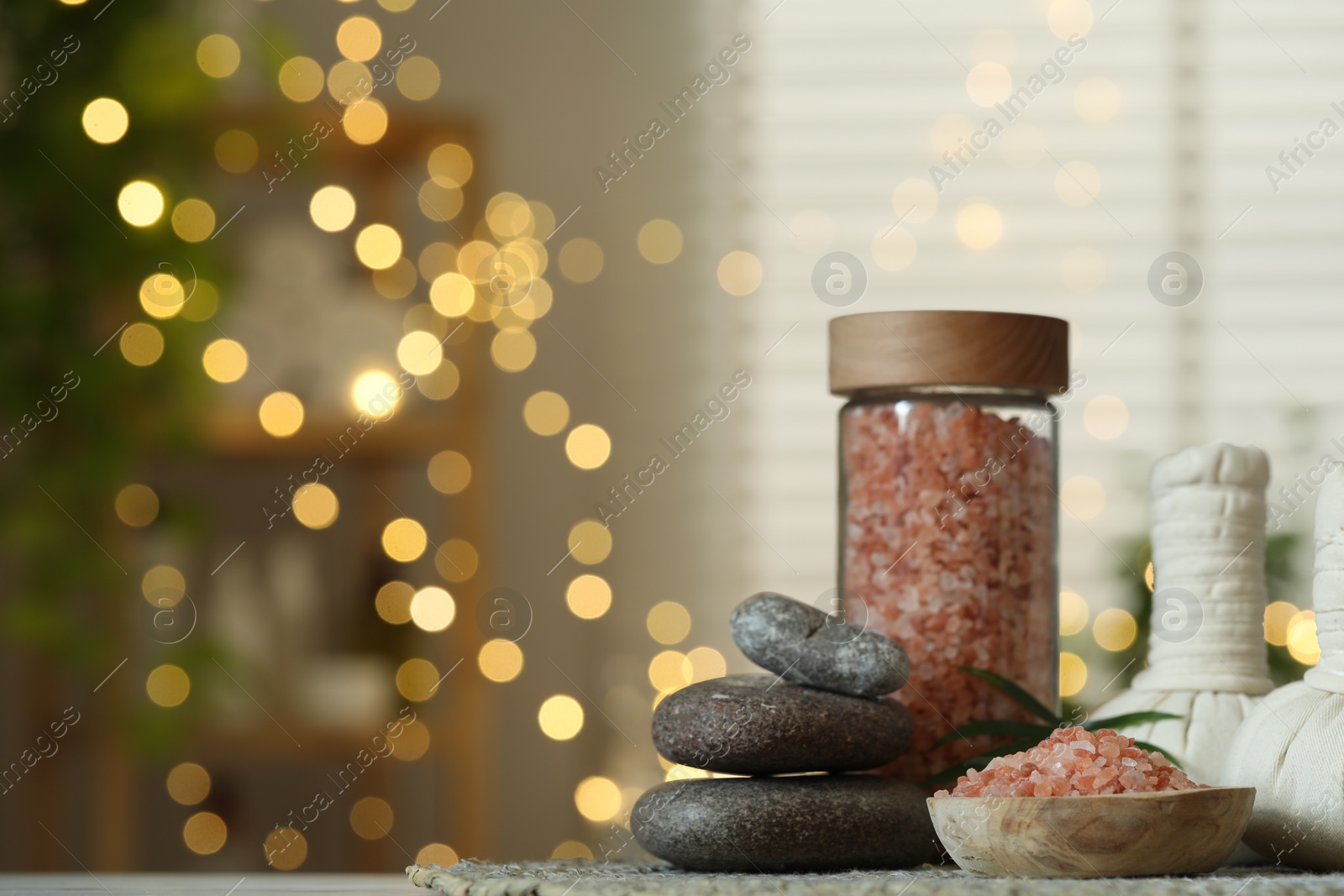 Photo of Spa composition. Herbal bags, sea salt and stones on table indoors, space for text