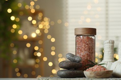 Photo of Spa composition. Herbal bags, sea salt and stones on table indoors, space for text